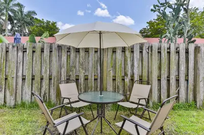 a table and chairs with an umbrella in front of a fence at Fort Lauderdale Family Bestseller in Fort Lauderdale