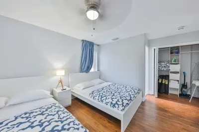 a white bedroom with two beds and a window at Hard Rock Family House in Fort Lauderdale