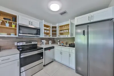 a kitchen with white cabinets and a stainless steel refrigerator at Jungle Happiness Villa STR-2651 in Hollywood