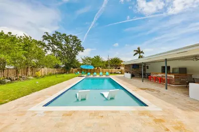 a swimming pool with two white chairs in a yard at A star is born villa in Hallandale Beach