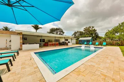 a swimming pool with an umbrella next to a house at A star is born villa in Hallandale Beach