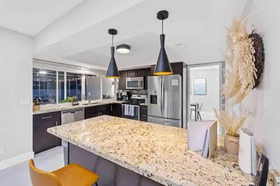 a kitchen with a granite counter top and appliances at SUN VILLA Heated Pool Near Hard Rock & Beach in Hollywood
