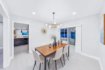 a dining room with a wooden table and white chairs at SUN VILLA Heated Pool Near Hard Rock & Beach in Hollywood
