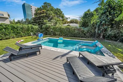 a swimming pool with two chairs and a wooden deck at The Design District Pool House in Miami