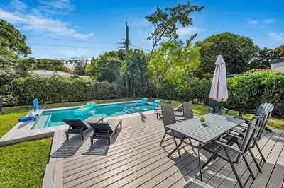 a deck with a table and chairs next to a pool at The Design District Pool House in Miami