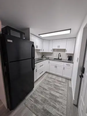 a kitchen with a black refrigerator and white cabinets at PrimeStay Modern Studio in Prime Location in Hollywood