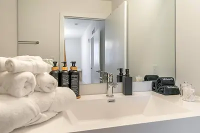a bathroom with a sink and a mirror and towels at Coastal 2BR-2BA Oasis Beach Pool Parking EV Estation in Hallandale Beach