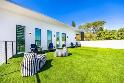 a backyard with two chairs on a green lawn at Up to 10 Guests! Design District Villa in Miami