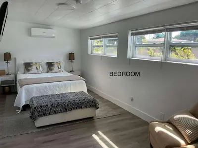 a bedroom with a bed and a couch and two windows at Comfort Apartment Miramar in Miramar