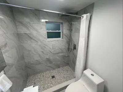 a bathroom with a shower with a toilet and a window at Comfort Apartment Miramar in Miramar