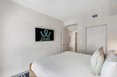 a white bedroom with a bed and a sign on the wall at Luxury Urban Comfort at The Crosby Miami - Central Location in Miami