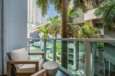 a balcony with a chair and a palm tree at Urban Oasis 2BR Loft Residence in Brickell in Miami