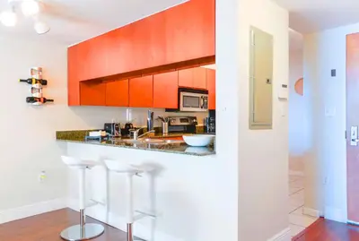 a kitchen with orange cabinets and white counter tops at Poolside Brickell Gem Stay in Miami