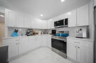 a white kitchen with white cabinets and appliances at Villa Shallat in Miami