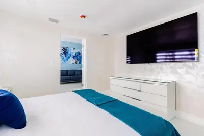 a white bedroom with a large television on the wall at Villa Shallat in Miami