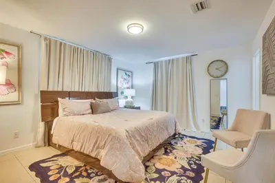 a bedroom with a bed and a chair and a clock at Walk to The Big Easy Casino Cozy Apt Near Beaches in Hallandale Beach