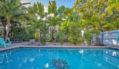 a swimming pool with palm trees in the background at Lazy Cabana- Pool Canal Wilton Drive in Fort Lauderdale
