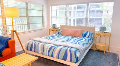 a bedroom with a bed with a striped blanket and windows at Lazy Cabana- Pool Canal Wilton Drive in Fort Lauderdale