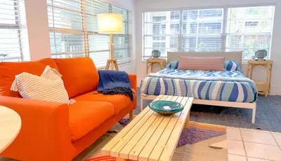 a living room with an orange couch and a bed at Lazy Cabana- Pool Canal Wilton Drive in Fort Lauderdale