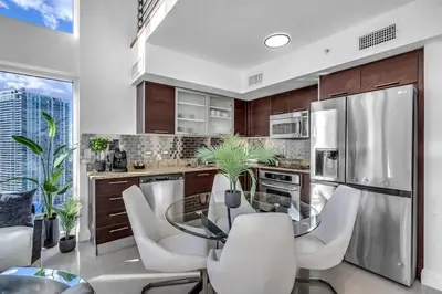a kitchen with a glass table and white chairs at Luxury 2BD Corner Loft with Stunning Miami River View in Miami