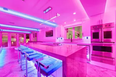 a pink kitchen with a large island with blue stools at Versace Mansion Neighbor (Floors 2 & 3) Sleeps 12 in Miami Beach