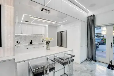 a white kitchen with a vase of flowers on the counter at Versace Mansion Neighbor (Floor 1,2,3) Sleeps 21 in Miami Beach