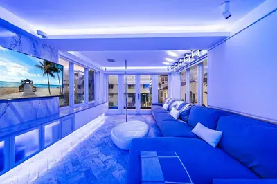 a living room with a blue couch and some windows at Versace Mansion Neighbor (Floor 1,2,3) Sleeps 21 in Miami Beach