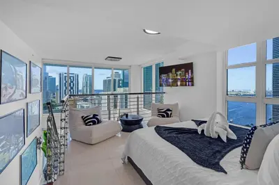 a bedroom with a bed and a balcony with windows at Brickell Residence 2BR Loft with amazing views in Miami