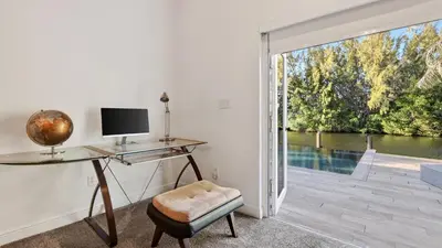 a desk and chair in a room with a sliding glass door at Riverside Veranda by AvantStay Waterfront Stay Infinity Pool Private Dock Easy Beach Access in Dania Beach