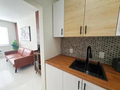 a kitchen with white cabinets and a sink and a couch at MB Playa Hotel & Apartments in Miami Beach