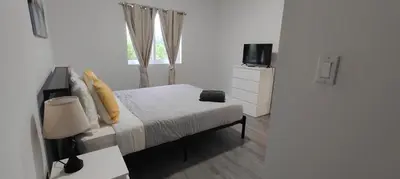 a white bedroom with a bed and a television at Spacious 3BR-2BA Apt near Downtown-Miami Airport in Miami