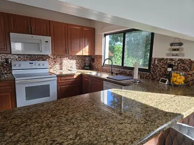 a kitchen with wooden cabinets and a marble counter top at Chacon in Miami