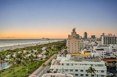 a view of a city and the beach at sunset at Crown Jewel of Ocean Drive- 2 story Penthouse, 4 Bedrooms & Private rooftop spa in Miami Beach