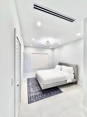 a white bedroom with a bed and a rug at Art District Stay Wynwood & Design District Nearby in Miami