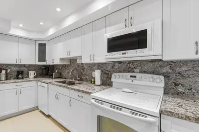 a white kitchen with a stove and a microwave at Oceanfront Condo with Direct Beach Access in Hollywood Beach