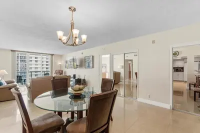 a dining room and living room with a glass table and chairs at Oceanfront Condo with Direct Beach Access in Hollywood Beach