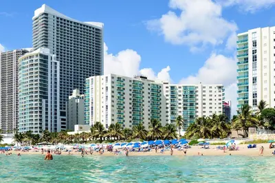 a beach with people in the water and buildings at Oceanfront Condo with Direct Beach Access in Hollywood Beach