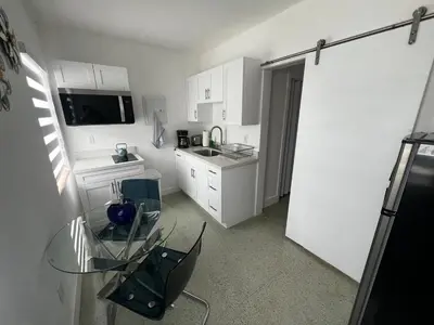 a kitchen with a glass table and a refrigerator at Villa Clara ROYAL-Little Havana in Miami
