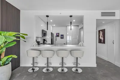 a kitchen with three bar stools in front of a counter at Huge Balcony Oceanfront 2 Bedrooms with Free Parking in Miami Beach