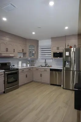 a kitchen with white cabinets and stainless steel appliances at Modern house with pool close to HARD ROCK in Pembroke Pines