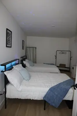 two beds in a room with white walls and wood floors at Modern house with pool close to HARD ROCK in Pembroke Pines