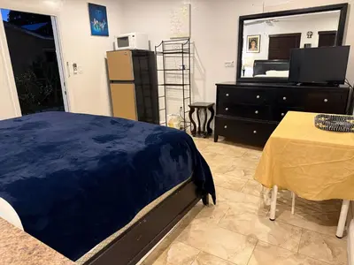 a bedroom with a bed and a table and a mirror at My Help Comes from The Lord Miami in Palmetto Bay
