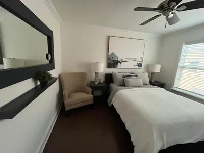 a bedroom with a bed and a chair and a ceiling fan at Beachside One Bedroom Condo with Pool Access in Hollywood