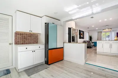 a kitchen with white cabinets and an orange and black refrigerator at Tropical Retreat- Heated Pool 3 Miles to the Beach in Fort Lauderdale