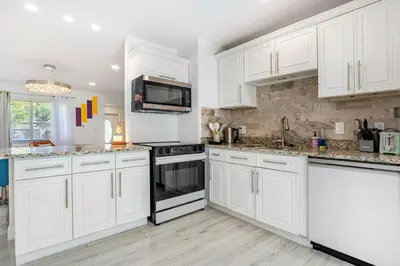 a white kitchen with white cabinets and a microwave at Tropical Retreat- Heated Pool 3 Miles to the Beach in Fort Lauderdale