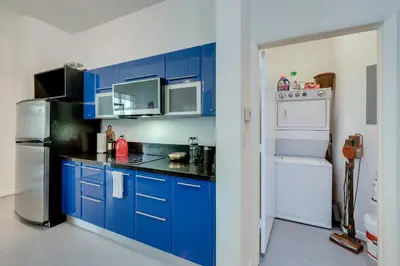 a kitchen with blue cabinets and a white refrigerator at The Vizcayne Vibe- Sauna Pool and Sundeck in Miami