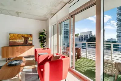 a living room with red chairs and a table and a large window at Midtown Rouge- Condo with City Views Pool & Gym in Miami
