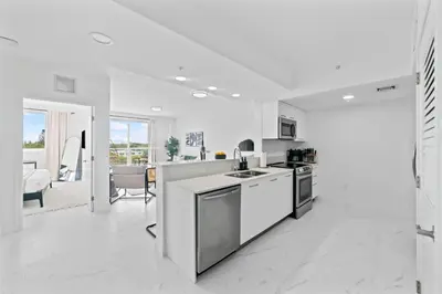 a kitchen with white appliances and a living room at Pool & Gym | King Bed | Downtown Hollywood in Hollywood