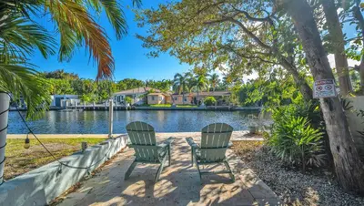 two chairs in front of a lake with houses at Take It Easy - Studio Pool Waterfront in Fort Lauderdale