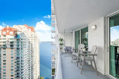 a balcony with a table and chairs and a view of the water at Sky-High Urban Sanctuary with Coastal Glimpses in Miami